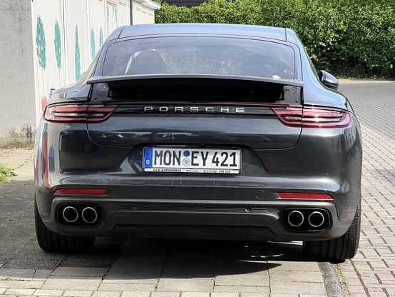 Das Bild zeigt die Rückseite eines schiefergrauen Porsche Panamera mit dem Wort 