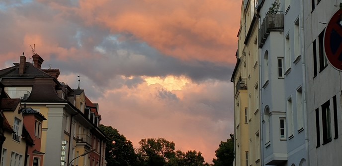 Links und rechts Häuserreihen und am Himmel rosa Wolken.