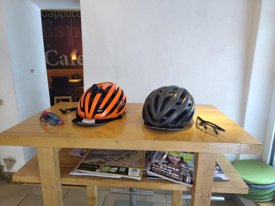 Zwei Helme und zwei Fahrradbrillen liegen auf einem Tisch.