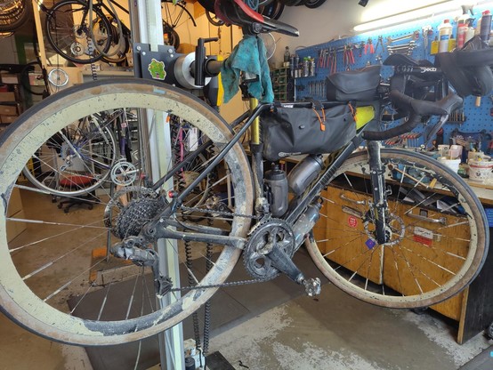 Ein dreckiges Rennrad in einem Montageständer in einer Fahrradwerkstatt.
